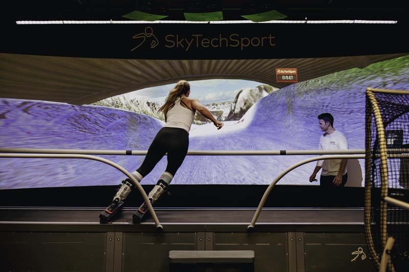 Woman skiing on the SkyTechSport ski simulator with an instructor at Home Mountain in Los Angeles